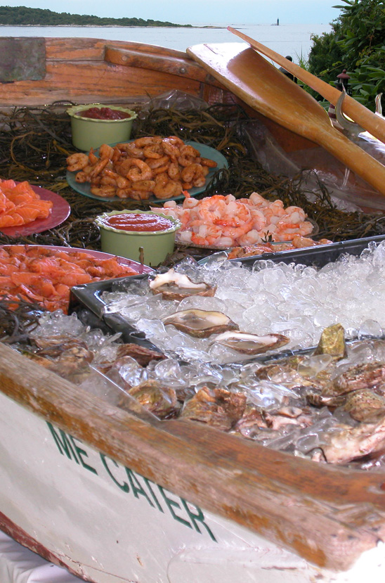 An antique dinghy is used to display a raw bar featuring freshly shucked oysters, steamed and spiced shrimp, and Maine cured salmon.