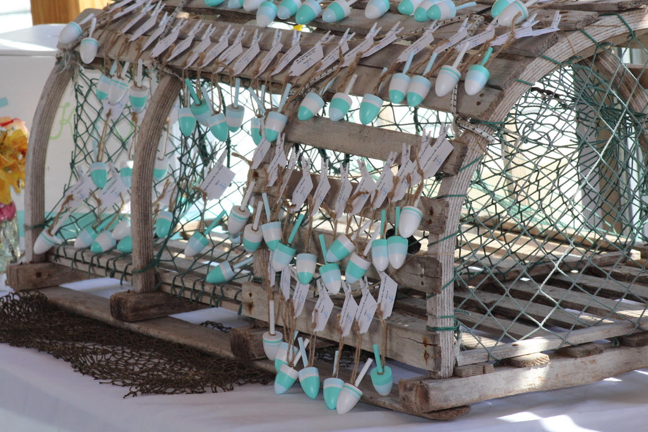 Small lobster buoys adorn a lobster trap and serve as seating cards for guests at a Maine Maritime Museum wedding.
